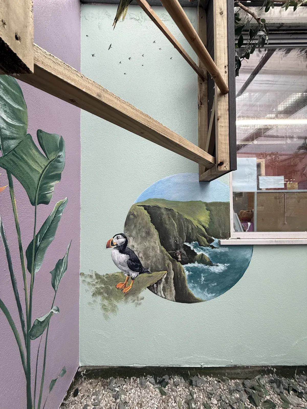 A puffin on a clifftop above the Atlantic, painted on a mint green wall