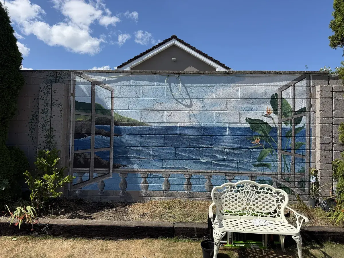 A trompe l'oeil mural of open shutters onto a sea view, painted on a garden wall