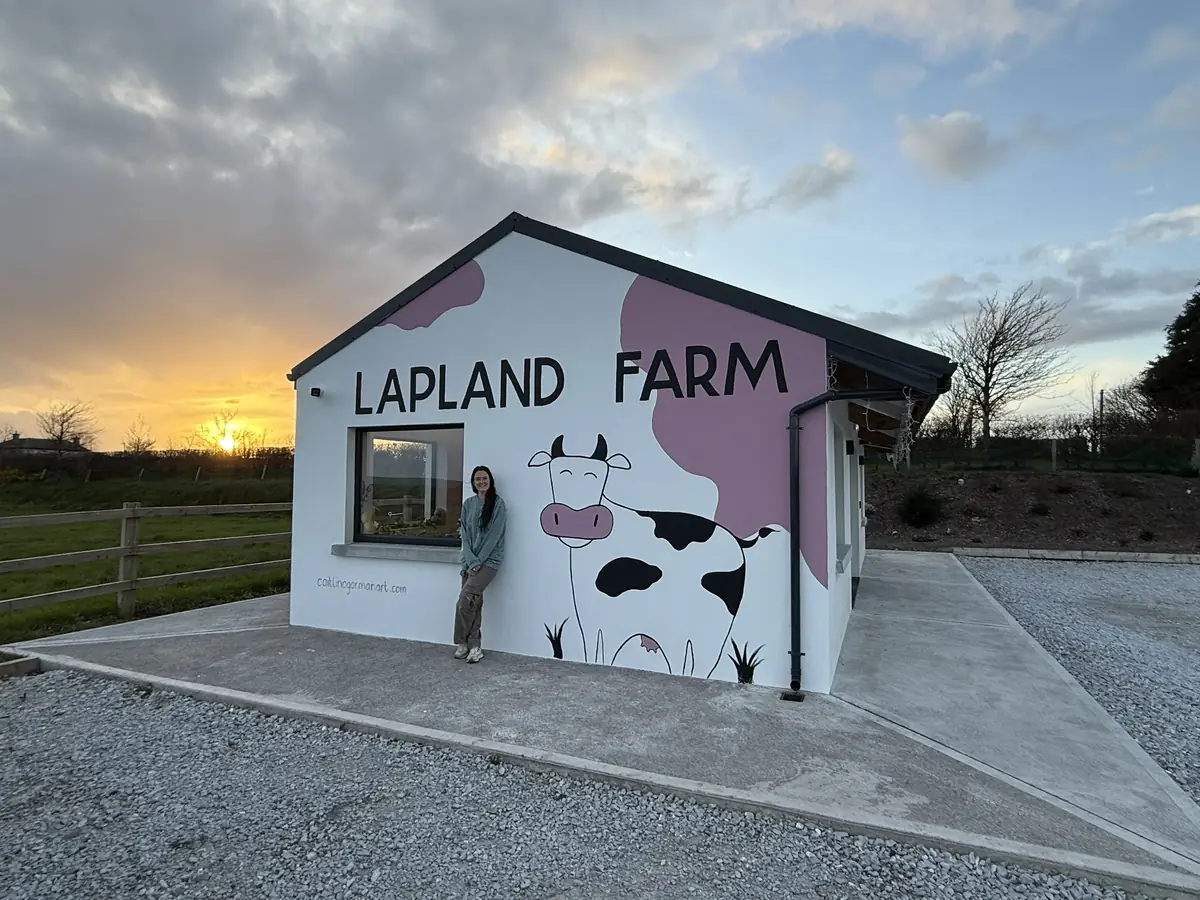 A hand-painted cow and the words Lapland Farm across a gable wall at sunset